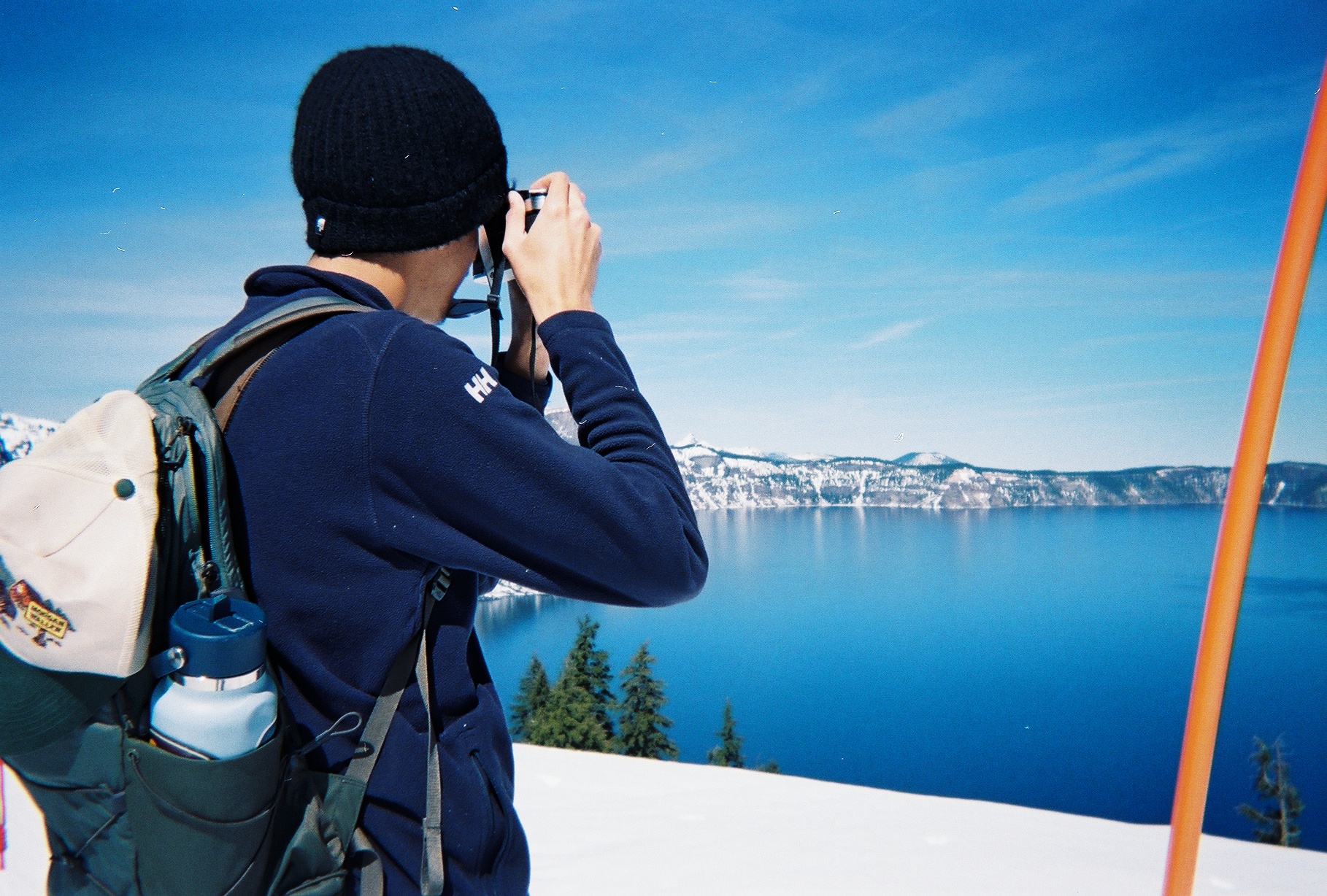 Thomas Paduraru holding his camera overlooking a snow-ringed volcanic lake